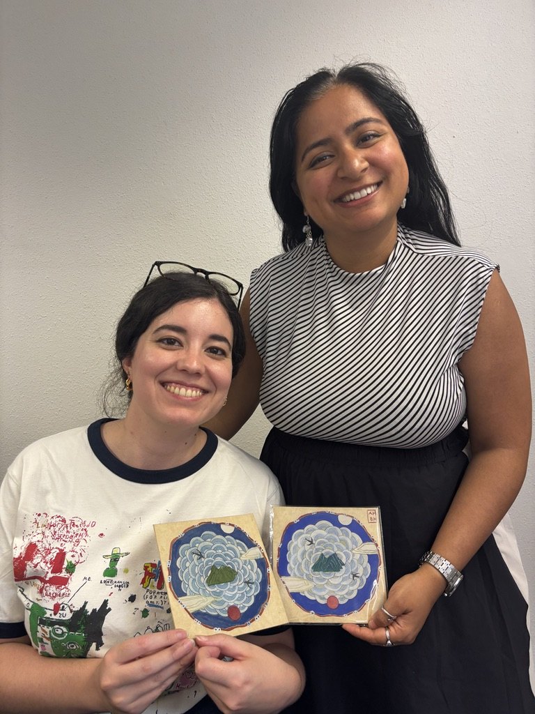 Two students smiling with finished Minhwa paintings